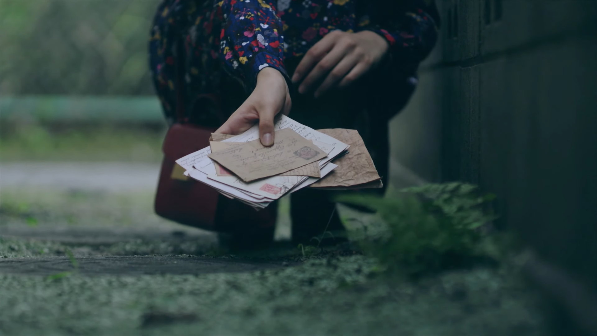 Hyunjin crouching and holding out a stack of letters.